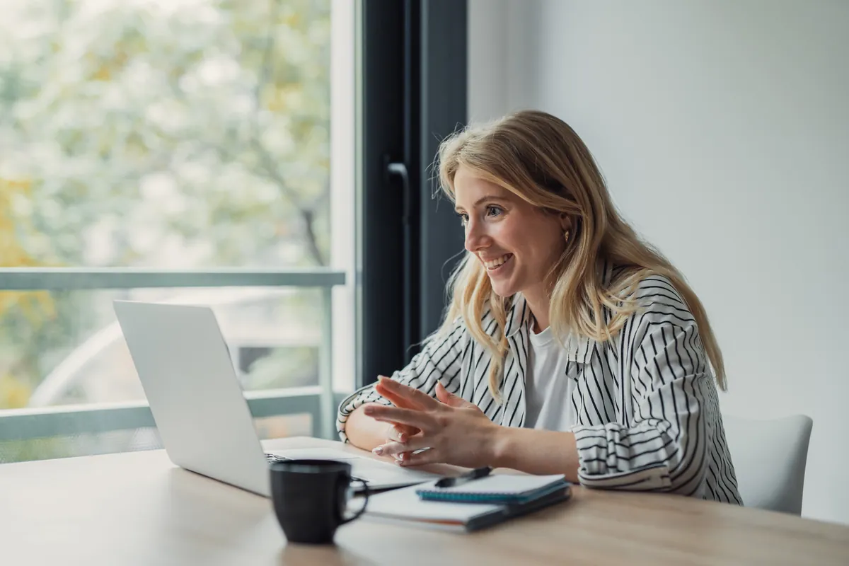 Manager smiling during a video call on her laptop in a bright office
